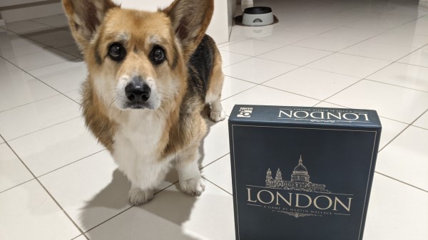 Chester the corgi standing beside a copy of the board game London.